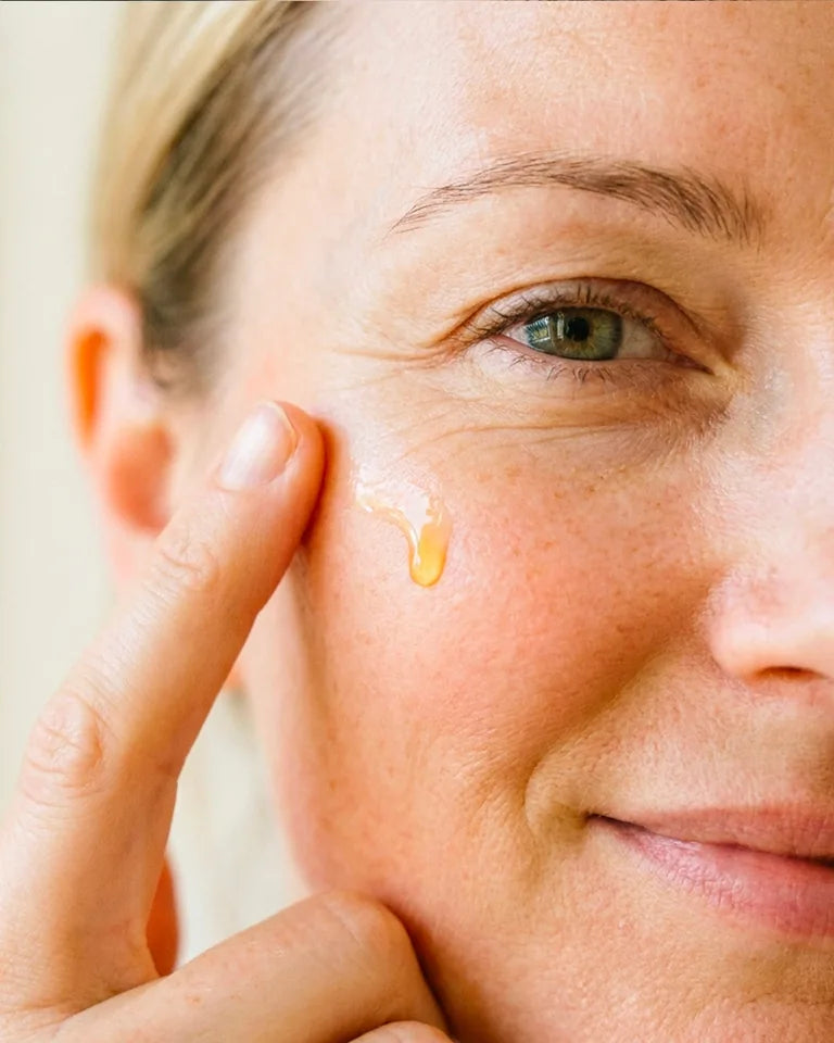 A woman applies serum to her cheek