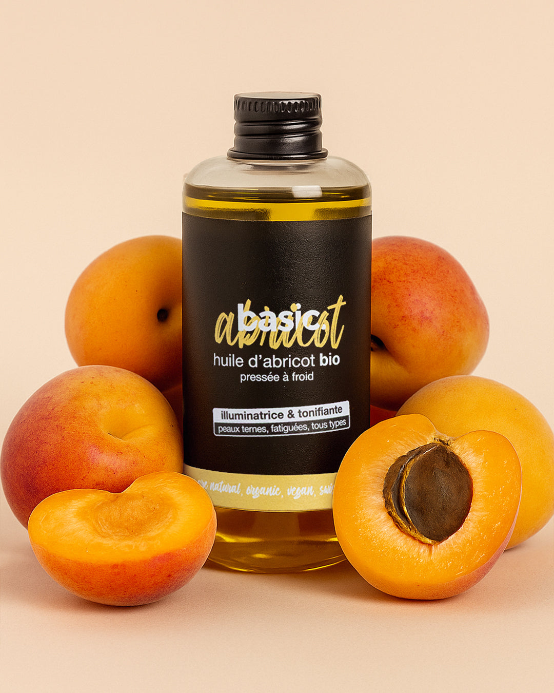 Flacon d'huile d'abricot bio Basic Cosmetics entouré d'abricots frais