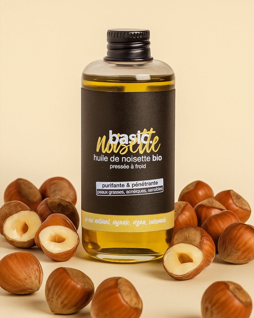 Flacon d'huile de noisette bio Basic Cosmetics entouré de noisettes